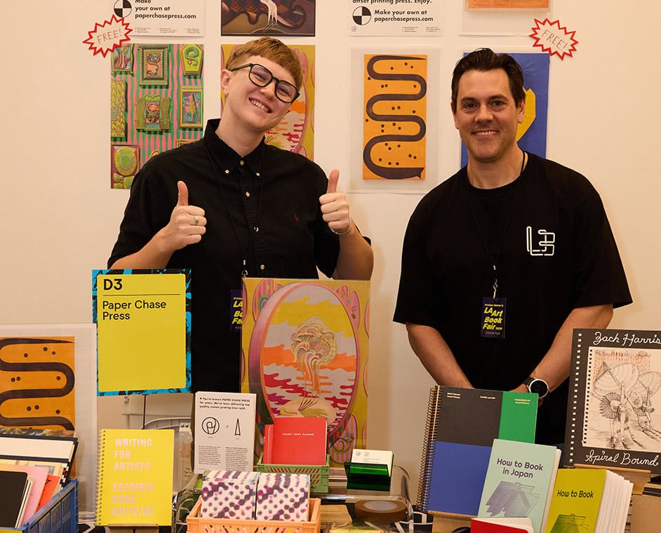 Hemlock representatives smiling from behind their booth at LA Art Book Fair