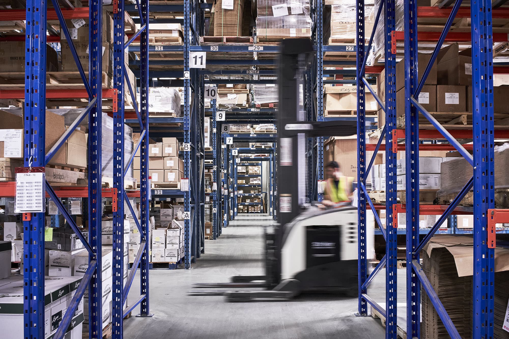 Image of a forklift moving through an expansive warehouse.