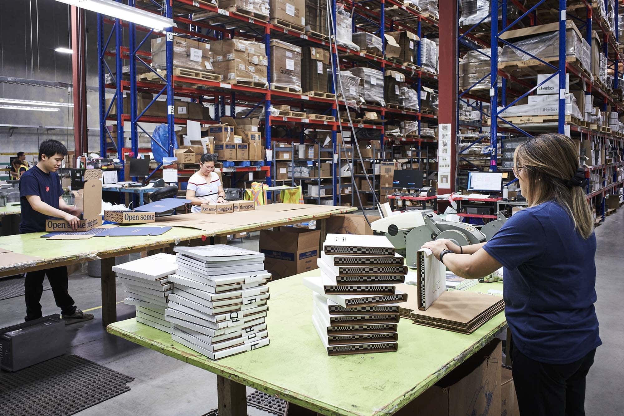 Workers packing orders into individual mailers for shipping.